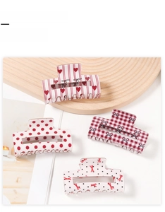 Set of four red patterned hair claw clips featuring hearts and dots on a wooden tray