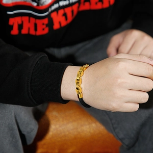 Detail of men's black braided leather and gold steel chain bracelet on a wrist