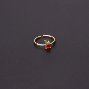 Macro detail of apple-shaped ring with red zircon and green stones on a gold band