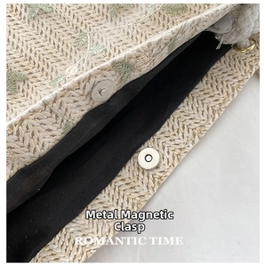 Detail of straw tote bag showing double metal magnetic buckles and black inner lining