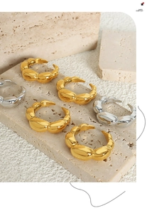 Macro detail of bold wave textured gold and silver rings on beige travertine stone