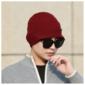 Close-up of wine red knitted beanie with thick ribbed texture and side logo detail