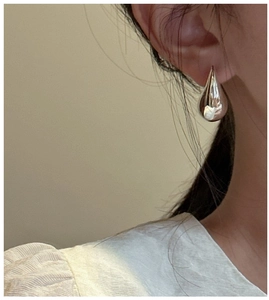 Close-up of a model wearing elegant silver hollow teardrop earrings with a mirror finish