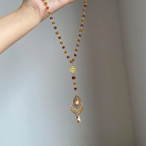 Détail du collier de perles ethniques avec cristal ambré et pendentif doré ciselé