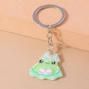 Close-up of cute green acrylic frog keychain with white polka dots and silver metal ring