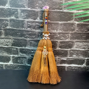 Detail of brown crystal witch broom with skull charm and purple gemstone handle