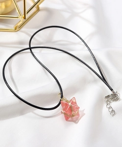 Detail of pink crystal star pendant with gold wire wrapping on white silk fabric