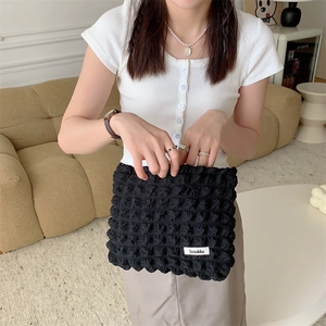 Detail of black cloud puff makeup bag showing soft pleated texture and woven brand label