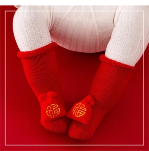 Detail of red baby Christmas sock with lucky bag embroidery and soft knit texture