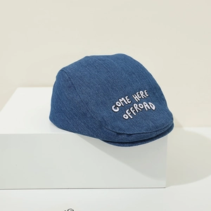 Detail of navy denim baby beret featuring white 3D embroidery and vintage texture