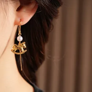 Golden rocking horse drop earrings with pearls shown on model in a vintage luxury style