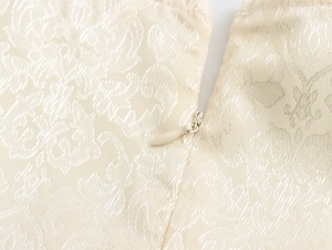 Détail macro d'une fermeture éclair invisible sur une robe en tissu jacquard crème