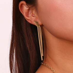 Detailed shot of 18K gold geometric earrings with tiered snake chain tassels on ear