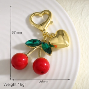 Détail d'un porte-clés cerise rouge montrant les dimensions et le fermoir cœur doré