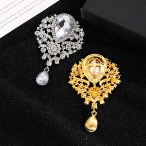 Macro detail of crown brooches with teardrop crystals and secure safety pin back