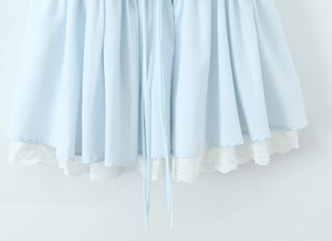 Gros plan sur l'ourlet de robe bleu clair avec broderie de dentelle blanche et texture du tissu