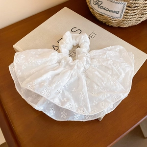 Gros plan d'un chouchou blanc brodé ajouré sur un livre ancien avec décor floral