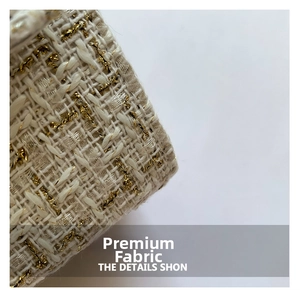 Close-up of white tweed fabric with woven gold metallic threads and luxury texture