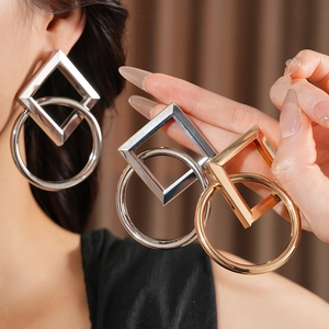 Détails des boucles d'oreilles géométriques dorées et argentées portées par un mannequin
