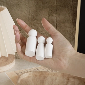 Three assorted wooden peg dolls held by hand for DIY creative painting and home decor