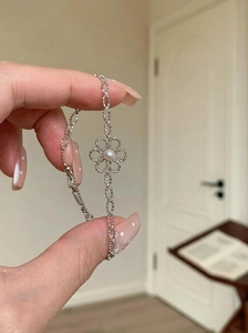 Détail d'un bracelet fleur argenté évidé avec perle blanche et chaîne à billes délicate