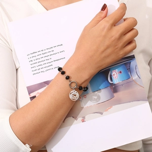 Detail of beaded bracelet with MAMA pendant worn on wrist with vintage paper background