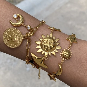Gold stainless steel bracelet set with sun, moon, and coin charms worn on wrist