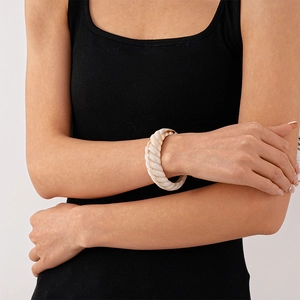 Macro shot of a twisted white resin bangle on a wrist showing shell-like texture details