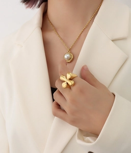 Detail of 18K gold-plated titanium steel ring and matching pearl necklace on model