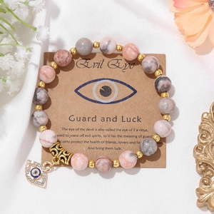 Detail of beaded evil eye bracelet with natural stone beads and card on white silk