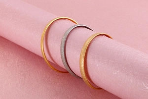 Macro detail of gold and silver matte textured titanium steel bangles on pink props