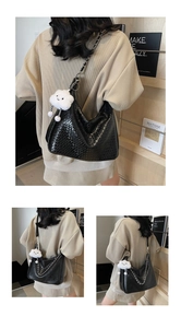 Detail of black woven shoulder bag featuring metal chain strap and white cloud charm