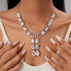 Luxe silver necklace featuring large rhinestones and HE letter pendant on model
