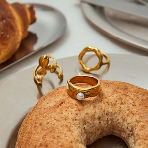 Three-piece gold titanium steel ring set with white pearl on a creative tray display