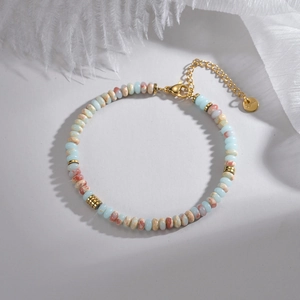Bohemian macaron bead bracelet with gold lobster clasp and round logo tag on white backdrop