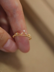 Macro shot of 18K gold plated S925 silver crown ring with cubic zirconia stones on finger