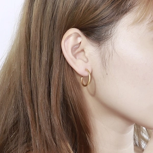 Close-up of golden twisted hoop earrings on model showing spiral texture and metallic luster