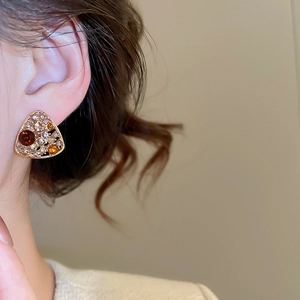 Detail of vintage gold triangle earring with amber rhinestones worn by a model