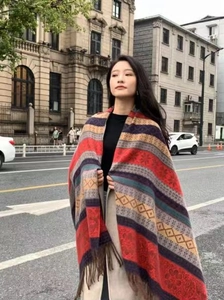 Close-up of ethnic striped scarf with colorful patterns and tassel details on a model