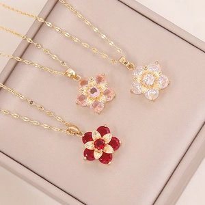 Multi-layer gold flower necklaces with red and pink zircon crystals on a beige box