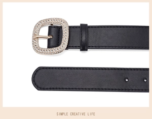 Detail of black leather belt featuring a gold buckle inlaid with sparkling rhinestones