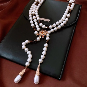 Detailed close-up of beaded floral necklace with large white teardrop pendants and vintage metal caps