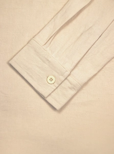 Detail shot of men's beige linen shirt showing buttoned cuff and high-quality fabric texture