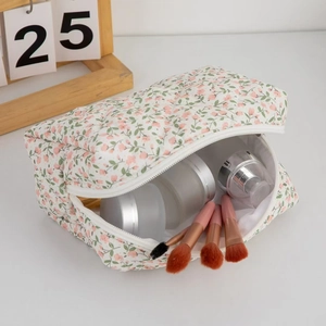 Quilted floral makeup bag with heart zipper detail holding brushes and cream jars