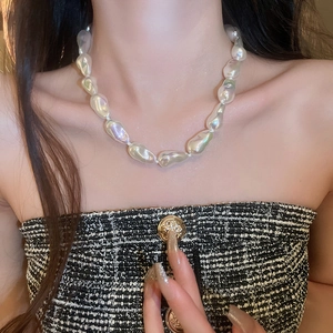 Close-up of irregular baroque pearl necklace featuring natural white luster on model