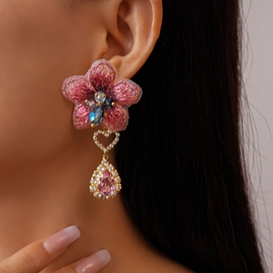 Détail de la boucle d'oreille fleur en tissu rose avec gemme goutte et cristal cœur