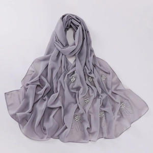 Macro detail of grey chiffon hijab featuring decorative pearls and floral rhinestone patterns