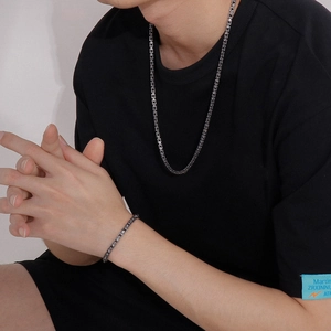 Detailed view of silver stainless steel box chain necklace and bracelet set on model