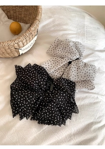 Detailed view of polka dot chiffon bow hair clips set against a minimalist background