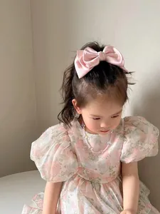 Close-up of pink satin bow hair clip worn by a young girl with silky texture detail